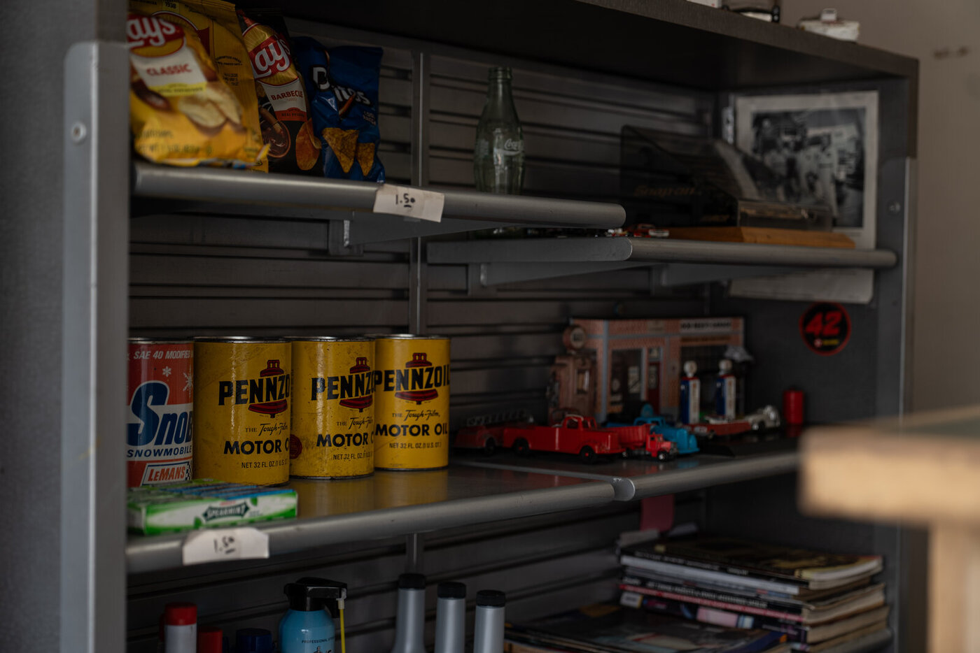 A shelf inside the shop with vintage Pennzoil cans, an old Coca-Cola bottle, and a model of the station