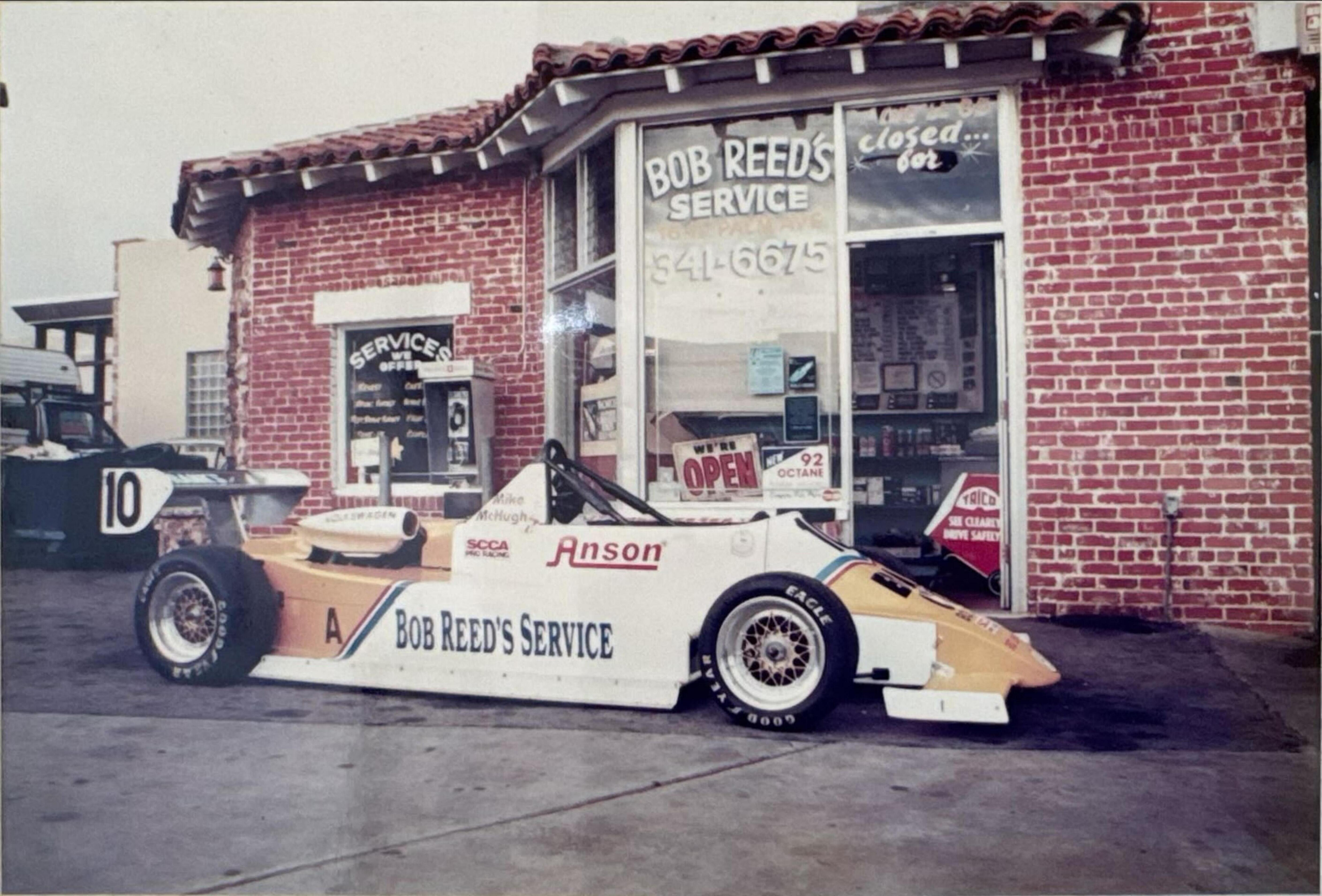 Vintage photo of Bob Reed's Service storefront with a race car parked out front
